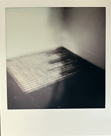Blurred Polaroid of a block of text written in dust, placed in the corner